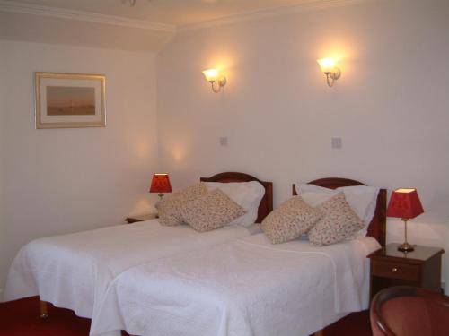 a bedroom with two beds with white sheets and lamps at Terrace hotel in Edinburgh