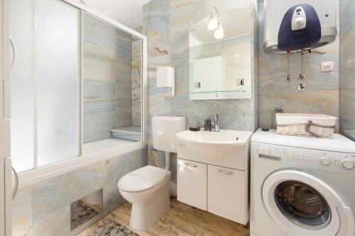 a bathroom with a toilet sink and a washing machine at Amigo Comfort Apartments in Split