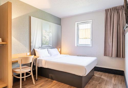 a hotel room with a bed and a desk and a window at B&B HOTEL Poitiers 1 Futuroscope in Chasseneuil-du-Poitou