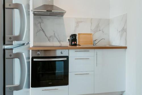 une cuisine avec des armoires blanches et un four noir dans l'établissement Washington 2, au Havre