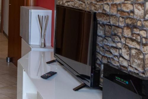 a television on a white stand with a remote control at lacasadikira in Lucca