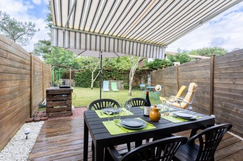 une terrasse avec une table, des chaises et un parasol dans l'établissement Maison proche du lac !, à Biscarrosse