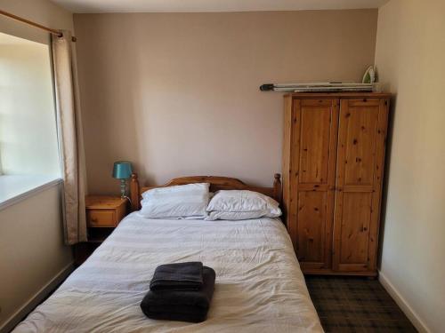 a bedroom with a bed and a wooden cabinet at Cosy country cottage beside Ancient Woodlands in Paxton