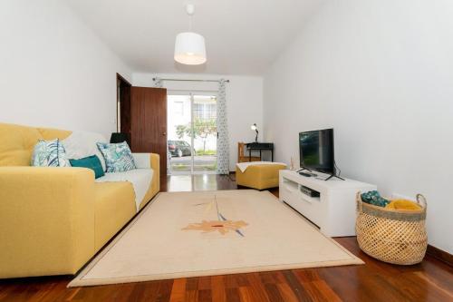 a living room with a yellow couch and a television at GuestReady - Monaco Nest in Ponta Delgada