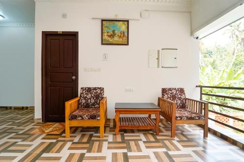 a room with two chairs and a table and a door at Fabhotel Star Inn Plus - Nr Kovalam Beach in Kovalam