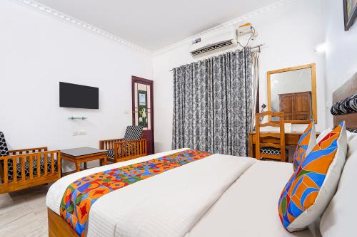 a bedroom with a bed and a desk and a television at Fabhotel Star Inn Plus - Nr Kovalam Beach in Kovalam
