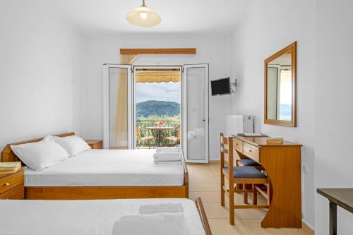 a hotel room with a bed and a desk and a window at Panorama studios 3 in Póndi