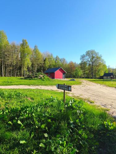 a sign in the grass next to a dirt road at Family vacation, 2 bedroom house - Red House in Lõupõllu