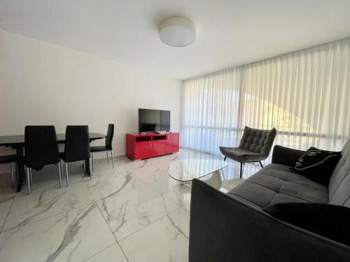 a living room with a couch and a table with chairs at 4 חדרים מרווחת 138 מ"ר חניה חינם קרוב לים in Eilat