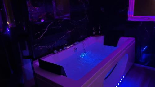 La salle de bains est pourvue d'une baignoire avec un éclairage violet. dans l'établissement Evasion balneo Fréjus, à Fréjus