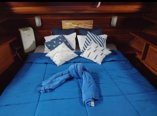 Una cama con sábanas y almohadas azules en un barco. en Passeio de barco na Escuna Ibiza, en Paraty
