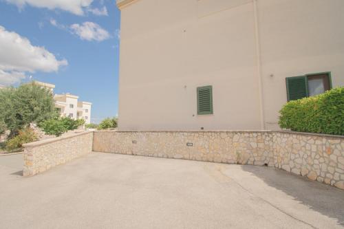 a white building with a stone wall next to a sidewalk at Casa Bellavista in Torre Canne