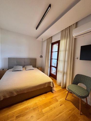 a bedroom with a bed and a chair and a window at Apartmán Zara in Komárno