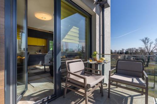 dwa krzesła i stolik na balkonie z kuchnią w obiekcie Sunset Resort 409 With Pool - Happy Rentals w mieście Fonyód