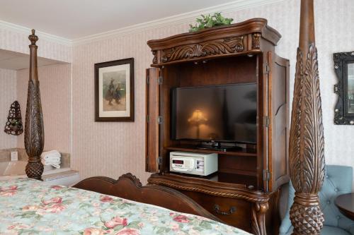 a bedroom with a bed with a television in a cabinet at Boardwalk Plaza Hotel in Rehoboth Beach