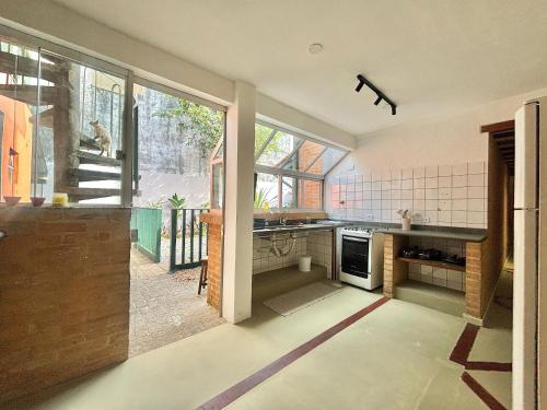 a kitchen with a large window and a stove at Manaca House_ refúgio charmoso_Centro c/ 2 quartos in Ubatuba