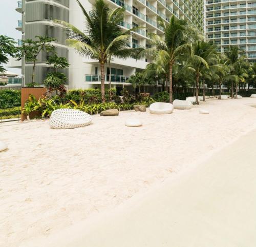 a sandy beach with palm trees in front of a building at The Sandscape Suite in Manila