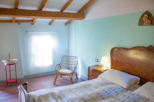 a bedroom with a bed and a chair and a window at Agriturismo Valpagliaro in Formignana