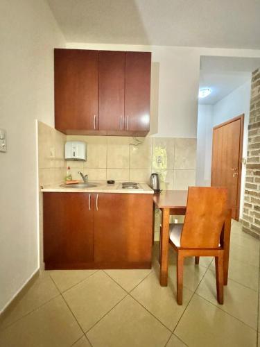 a kitchen with wooden cabinets and a table and a chair at Contessa Apartments in Budva