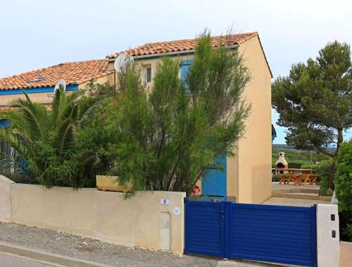 une maison avec une porte bleue devant elle dans l'établissement Mas de O, à Saint Pierre La Mer