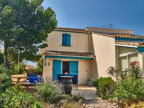 une maison avec des portes bleues et une table devant elle dans l'établissement Mas de O, à Saint Pierre La Mer