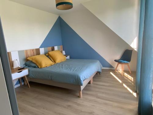 a bedroom with a bed with a blue accent wall at Maison vue mer prés avec SPA près des plages in Plouhinec