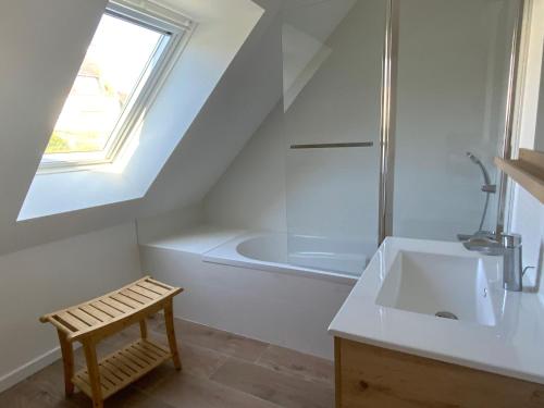 a white bathroom with a sink and a bath tub at Maison vue mer prés avec SPA près des plages in Plouhinec