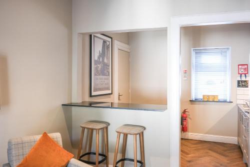 a kitchen with a counter and two stools at Glen Mhor Hotel at Uile-bheist 'Brewstillery' in Inverness