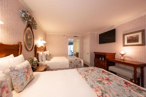 a hotel room with two beds and a desk at Boardwalk Plaza Hotel in Rehoboth Beach
