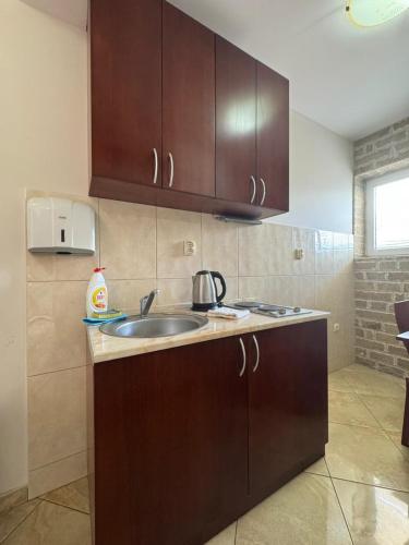 a kitchen with a sink and wooden cabinets at Contessa Apartments in Budva