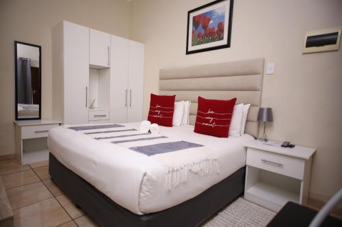 Un dormitorio con una gran cama blanca con almohadas rojas. en Twenty 4 Hr Self-Catering Accomodation, en Mthatha