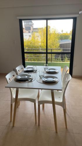 a dining room table with white chairs and a large window at Lo de Lupe in Colón