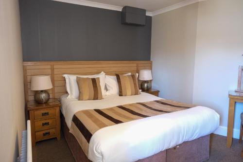 a bedroom with a large bed and two night stands at Glen Mhor Hotel at Uile-bheist 'Brewstillery' in Inverness