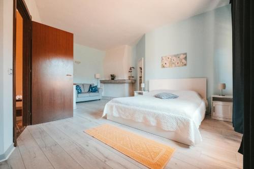 a bedroom with a white bed and a wooden floor at Villa Bella Salmagi - Surya Sardinia Holidays & Yoga in Capitana