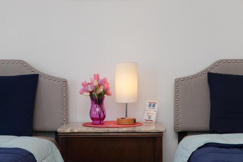 a vase of pink flowers on a table between two beds at 3 Bedroom Gem! King, Full & Twin Beds, Sauna with Free Parking plus more in Jersey City