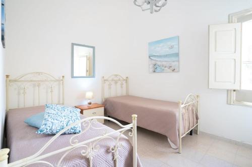 two beds in a bedroom with white walls at Villa Camilla by SALENTO OASIS in Porto Cesareo