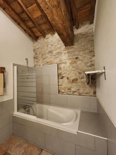 une baignoire dans une salle de bain avec un mur en pierre dans l'établissement Le Clos sainte Marie - Crouzette, à Cenne-Monestiès