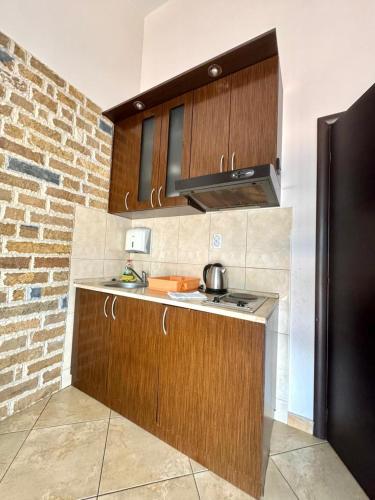 a kitchen with wooden cabinets and a brick wall at Contessa Apartments in Budva