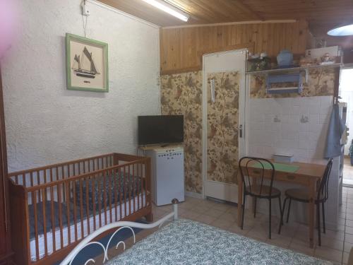 une petite pièce avec un berceau, une table et une télévision dans l'établissement Studio garrigue saint didier, à Saint-Didier