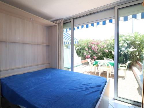 une chambre avec un lit bleu et une grande fenêtre dans l'établissement Studio Cabine avec terrasse ensoleillée, piscines, parking privé, à 500m de la plage - FR-1-307-133, au Grau-du-Roi
