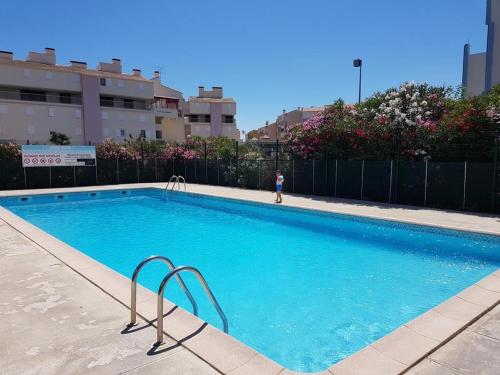 une grande piscine bleue avec une personne en arrière-plan dans l'établissement Studio Cabine avec terrasse ensoleillée, piscines, parking privé, à 500m de la plage - FR-1-307-133, au Grau-du-Roi