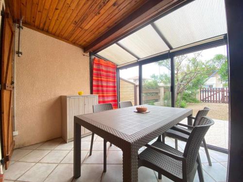une table et des chaises dans une pièce avec une fenêtre dans l'établissement Pavillon Climatisé 2p avec Grande Terrasse à 1500m de la Plage, Jusqu'à 4 Pers - FR-1-229C-78, à Port-la-Nouvelle