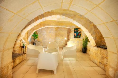 バレッタにあるMagestic palazzo, jacuzzi on roof terrace GOVAL-3の白い椅子とテーブルと石の壁のある部屋