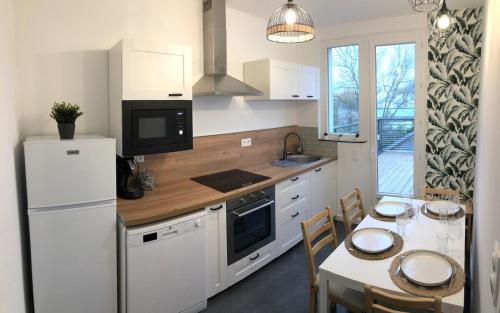 Il comprend une cuisine équipée d'un réfrigérateur blanc et d'une table avec des chaises. dans l'établissement Appartement 3 chambres - grande terrasse, à Saint-Nazaire