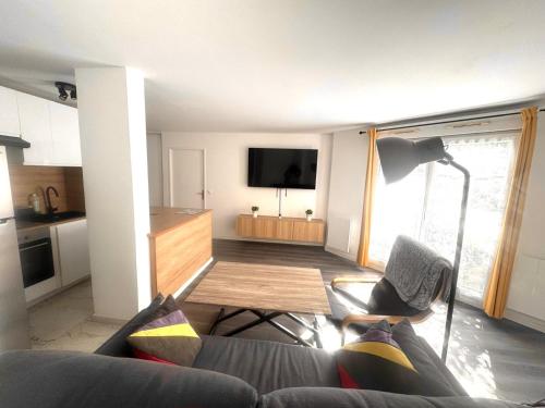 a living room with a couch and a table and a television at 24 7 Open Apartment Parking 15'Paris 5'Athletica bis in Saint-Gratien