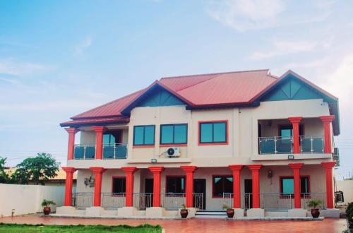 a house with red columns and a red roof at Michael’s Apartment Complex in Accra