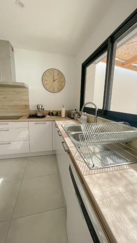 une cuisine avec un évier et une horloge murale dans l'établissement L’Oliveraie, à Narbonne