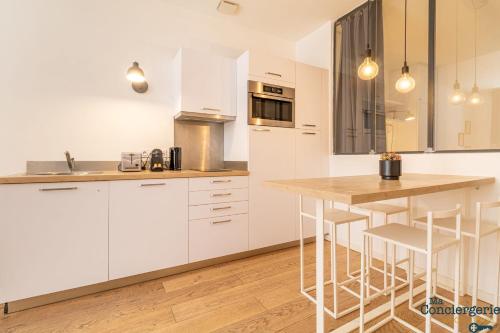 une cuisine avec des armoires blanches et un comptoir en bois dans l'établissement DV1 Le gris Chiné - Metro - Gare centre ville, à Toulouse