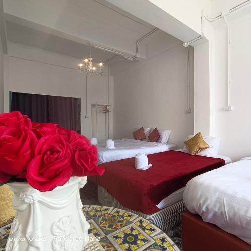 a bedroom with two beds and a red rose in a vase at MaHaNa Hostel Pattaya in Jomtien Beach