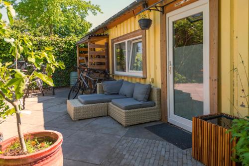 a patio with a couch and a window at Tiny house - fietsverhuur, eigen keuken en badkamer in Nijmegen